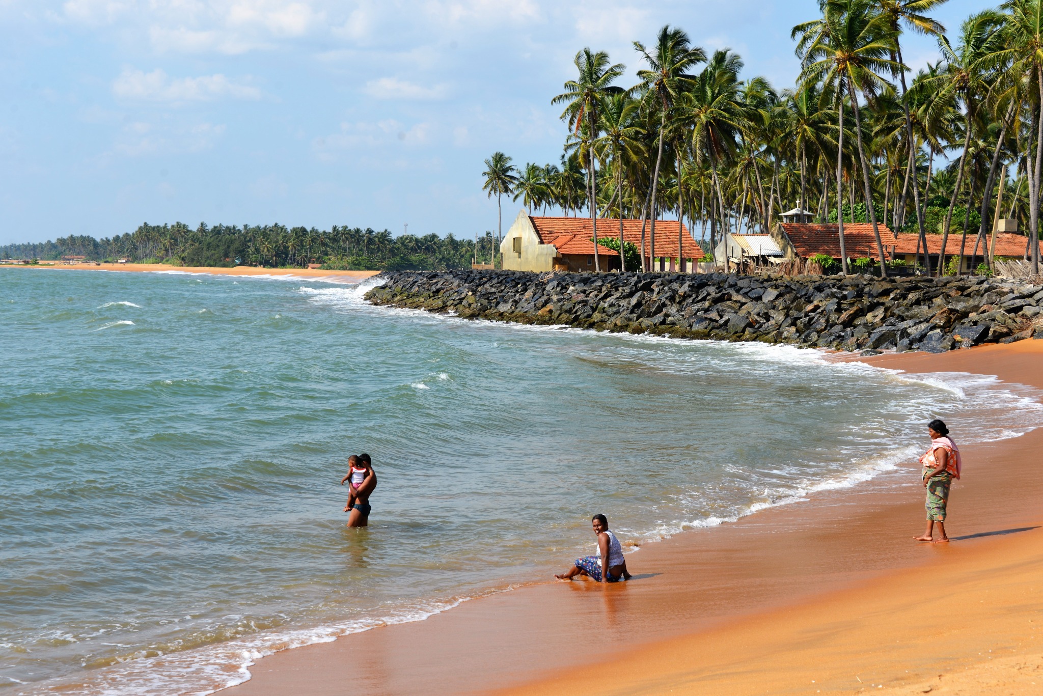 Menschen am Strand von Sri Lanka mit Palmen und Häusern entlang der Küste